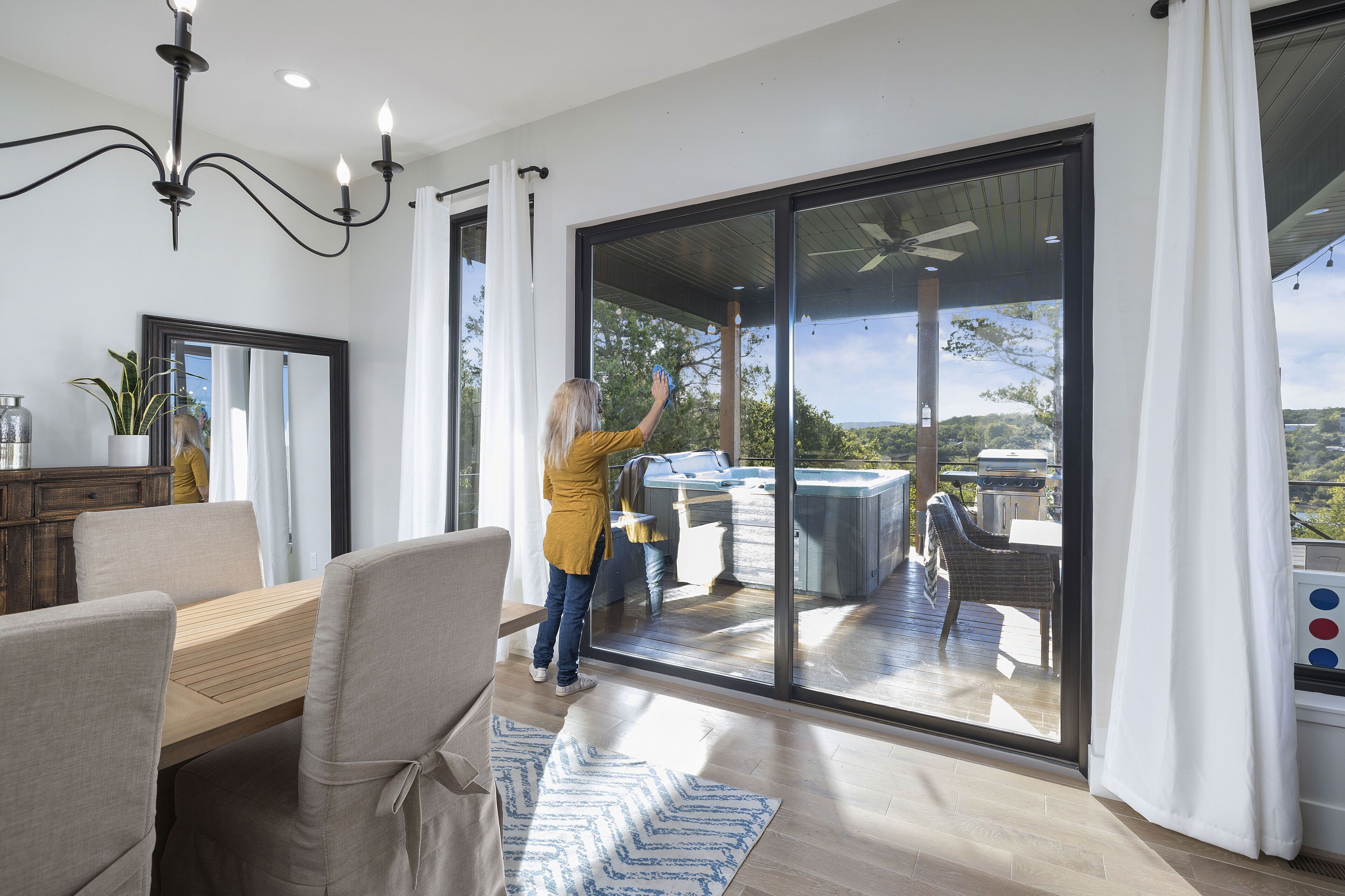 Un intérieur moderne comprenant un coin repas, une grande porte-fenêtre coulissante donnant sur une terrasse extérieure avec un jacuzzi et des sièges.