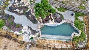 Vista aerea di una zona curata con piscina, sentieri in pietra e un pontile in legno.