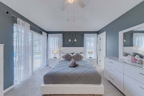 A bedroom with a bed, bedside tables, a ceiling fan, and a large mirror.
