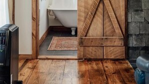 Un baño rústico con puerta de madera, una bañera y pared de piedra.
