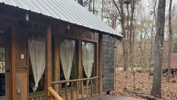 Una baita con veranda in legno, vasca idromassaggio e una scalinata che conduce all'ingresso.