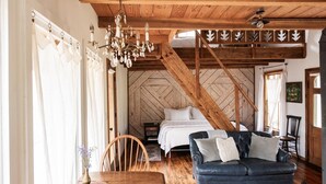 Una habitación acogedora con una cama, un sofá azul, una mesa de comedor de madera y una araña.