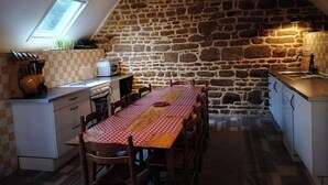 Eine gemütliche Küche mit einer Steinwand, einem Esstisch mit kariertem Tischlauf und einem kleinen Fenster über der Spüle.