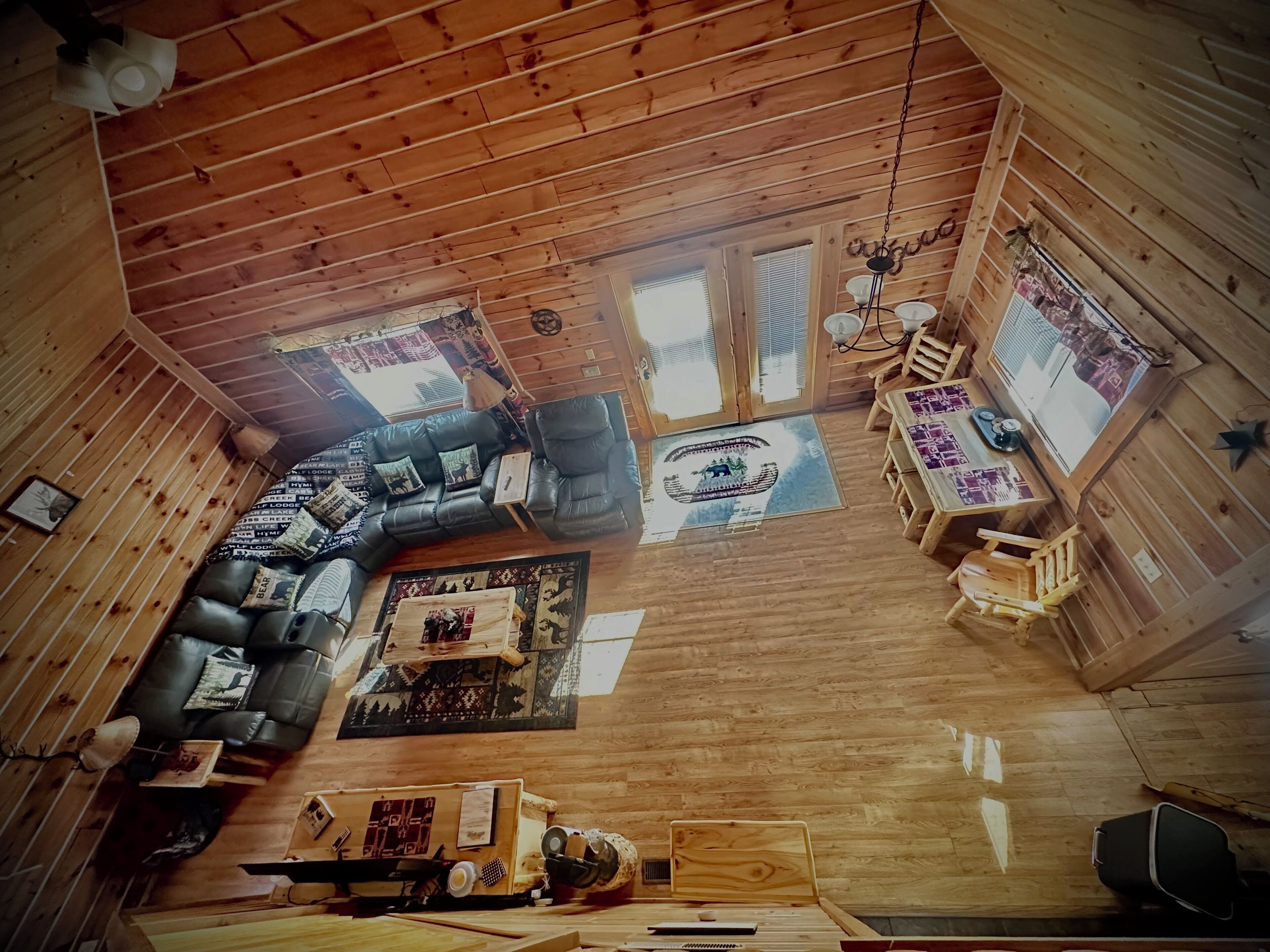 Un intérieur de chalet chaleureux avec un plafond en bois, un canapé d’angle, une table à manger et un petit coin cuisine.