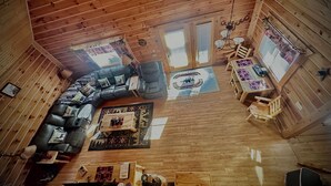 A cozy cabin interior with a wooden ceiling, a sectional sofa, a dining table, and a small kitchen area. - Cabin- no cleaning fees: Cranberry Fest, waterparks, trail riding for utv/atv (Warrens)