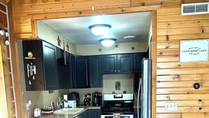 A cabin-style kitchen with wooden walls, a central island, and a built-in oven. - Cabin- no cleaning fees: Cranberry Fest, waterparks, trail riding for utv/atv (Warrens)