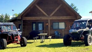 A wooden cabin with two ATVs parked in front. - Cabin- no cleaning fees: Cranberry Fest, waterparks, trail riding for utv/atv (Warrens)