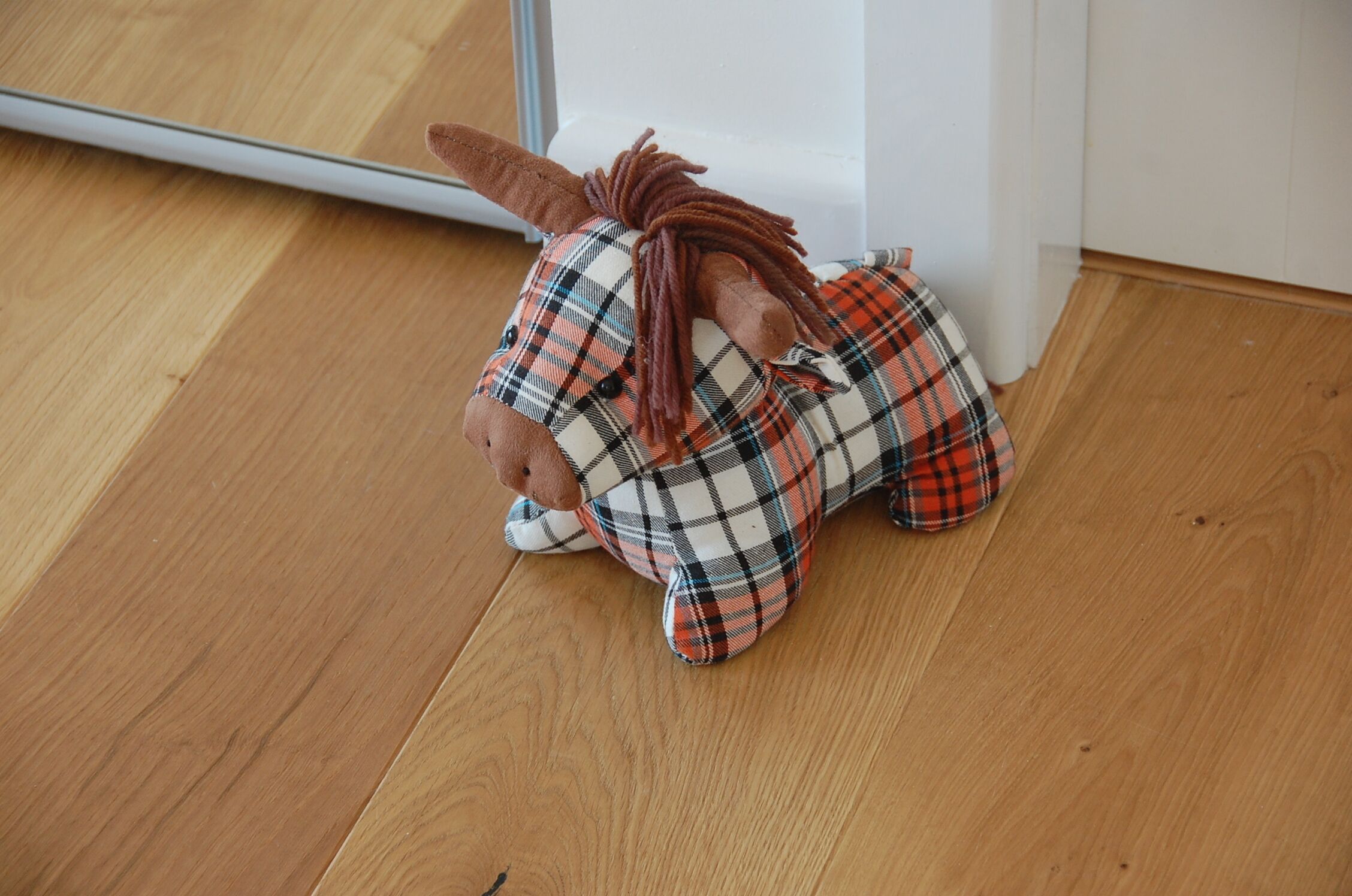 Un peluche con pijamas de cuadros sobre un suelo de madera.