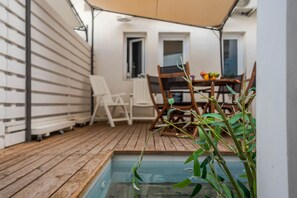 A wooden deck with a pool, white chairs, and a table with fruit. - Bow Suite with Hot Tub (Marina di Ragusa)