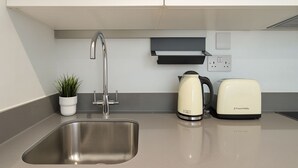A modern kitchen with a stainless steel sink, a kettle, and a toaster. - The Kingston Upon Thames Apartme (Kingston Upon Thames)