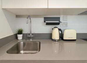 A modern kitchen with a stainless steel sink, a kettle, and a toaster. - The Kingston Upon Thames Apartme (Kingston Upon Thames)
