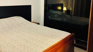 A bedroom with a wooden bed, a wardrobe, and a nightstand.