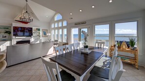 Una cocina amplia con comedor, ventanas grandes y vista al océano.