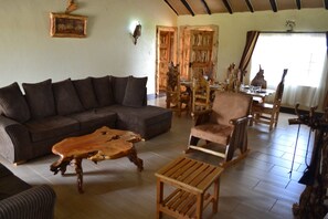 Un salon chaleureux avec un canapé d’angle, une table basse en bois et un fauteuil à bascule.