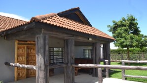A rustic building with a tiled roof, a wooden door, and a porch with a bench. - Burguret Kilele Guest House & Restaurant (Nanyuki)