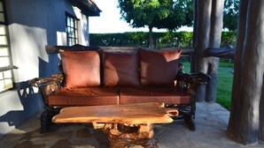A wooden coffee table with a rustic design, placed on a stone floor. - Burguret Kilele Guest House & Restaurant (Nanyuki)