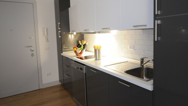 A modern kitchen with white cabinets, stainless steel appliances, and a white countertop.