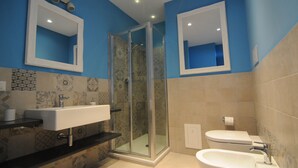 A bathroom with a glass-enclosed shower, a sink with a countertop, and a bathtub.