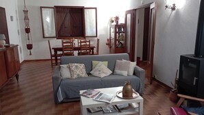 Een woonkamer met een grijze bank, een houten eettafel en een televisie.