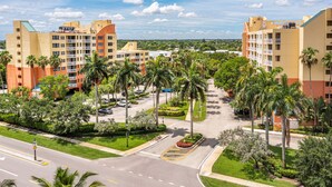 A multi-story hotel with balconies, surrounded by palm trees and a parking lot.