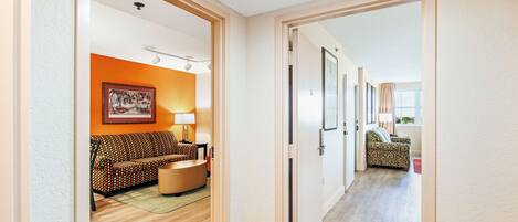A hallway leading to a living area with a sofa, a lamp, and a patterned rug.
