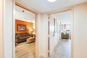 A hallway leading to a living area with a sofa, a lamp, and a patterned rug. - (Weston)