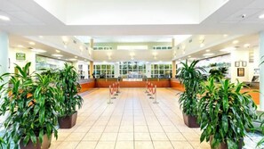 A spacious lobby with a tiled floor, potted plants, a reception desk, and a glass partition. - Vacation Village at Bonaventure (Weston)