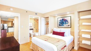A hotel room with a bed, a wardrobe, a bathroom, and a kitchenette.