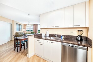A modern kitchen with white cabinets, a granite countertop, and a dishwasher.