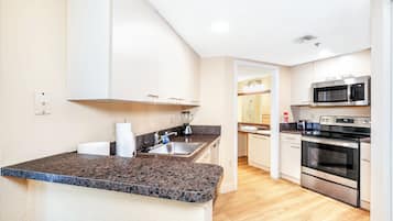 A modern kitchen with granite countertops, stainless steel appliances, and white cabinetry.