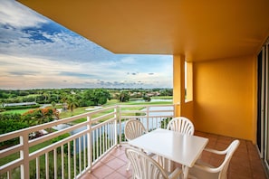 A balcony with a white table and chairs, overlooking a green landscape with a river and palm trees. - Vacation Village at Bonaventure (Weston)
