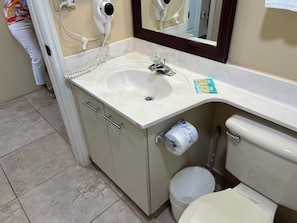 Ein Badezimmer mit Waschbecken, Spiegel, Toilette und MĂŒlleimer.