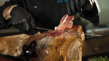 Alguém corta um pedaço grande de carne em uma tábua de madeira.