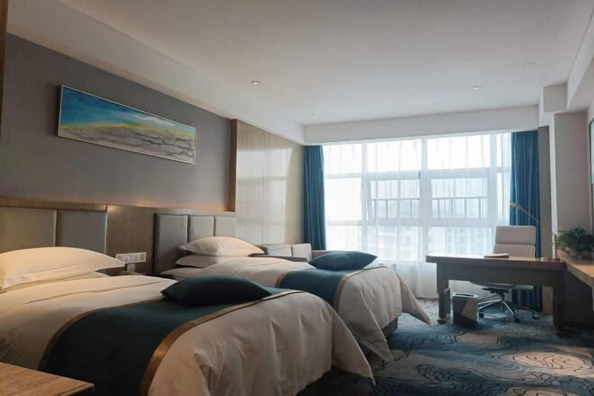 Habitació d'hotel amb dos llits, un escriptori i un gran finestral.