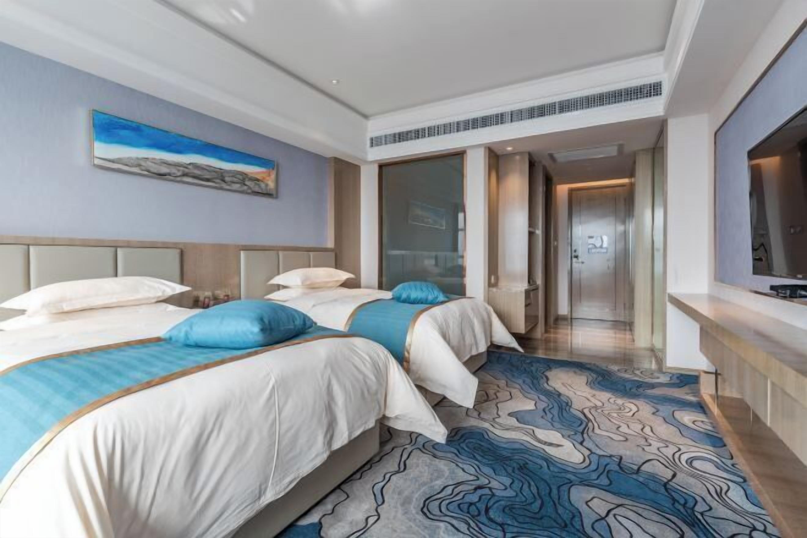 Una habitación de hotel con dos camas, un ventanal grande y un televisor de pantalla plana.