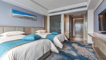 Una habitación de hotel con dos camas, un ventanal grande y un televisor de pantalla plana.