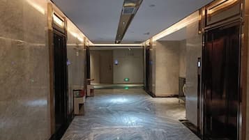 A hallway with marble flooring, elevator doors, and a sign on the wall.