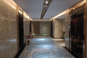 A hallway with marble flooring, elevator doors, and a sign on the wall.