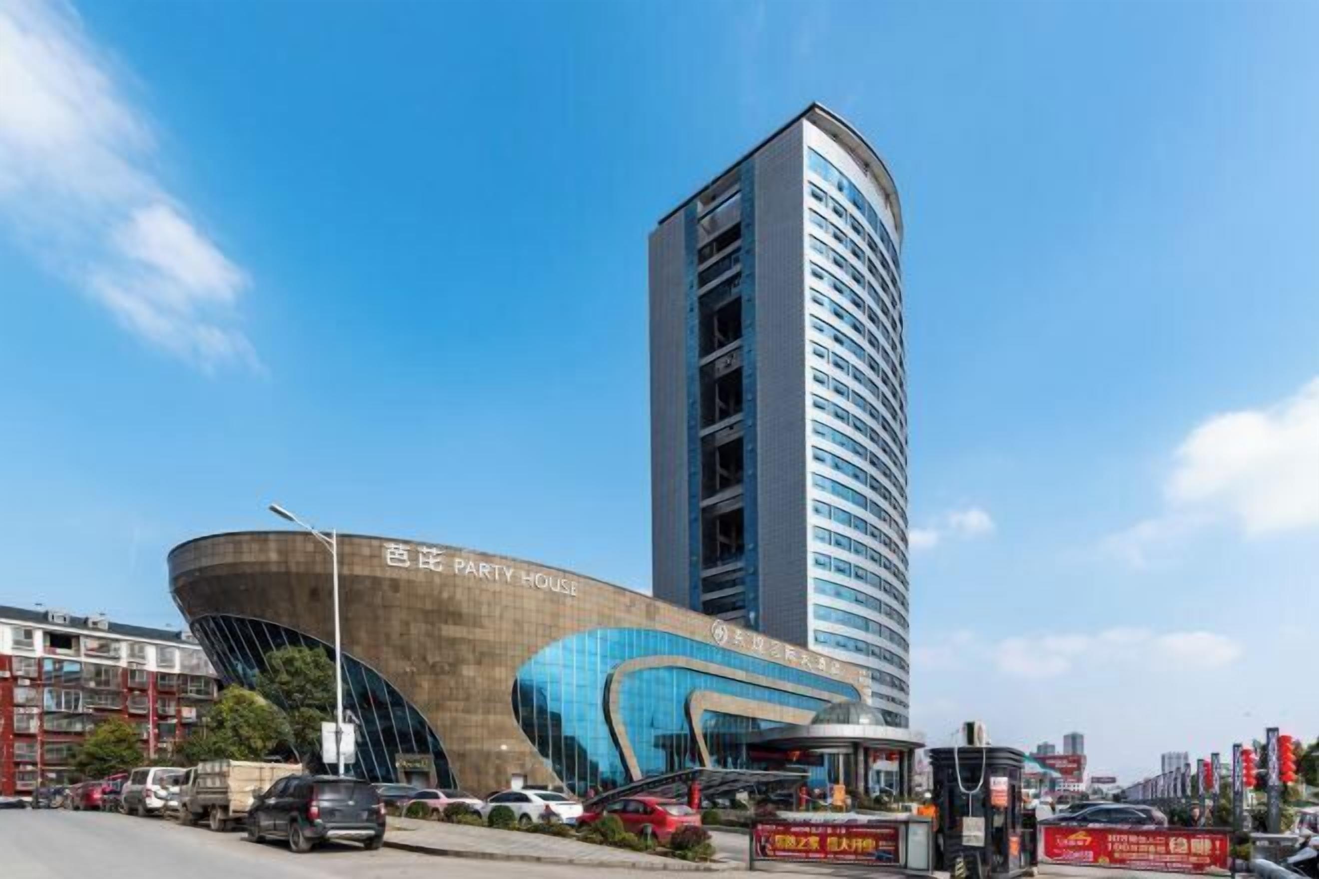 Un edificio moderno con fachada curva y una estructura alta contigua.
