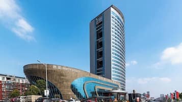 Un edificio moderno con fachada curva y una estructura alta contigua.