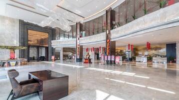A spacious lobby with a high ceiling, a reception desk, and a seating area.