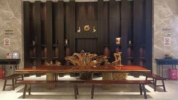 A long dining table with benches in a room with vertical wooden panels and a marble floor.