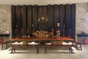 A long dining table with benches in a room with vertical wooden panels and a marble floor.