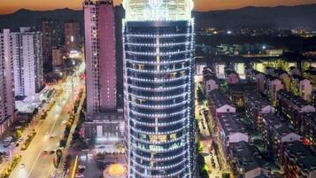 A high-rise building with a circular top, surrounded by other tall buildings and a busy street below.