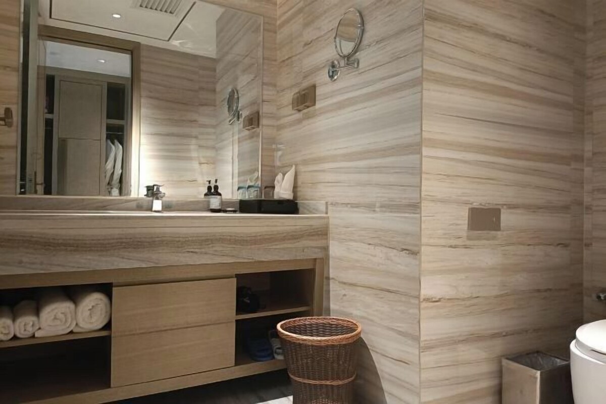 Un baño con tocador de madera, un espejo grande y un lavamanos montado en la pared.
