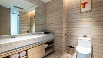 Un baño moderno con un mueble de tocador de madera, un espejo grande y un inodoro.