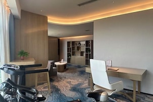 Quarto de hotel moderno com esteira, escrivaninha e carpete estampado.
