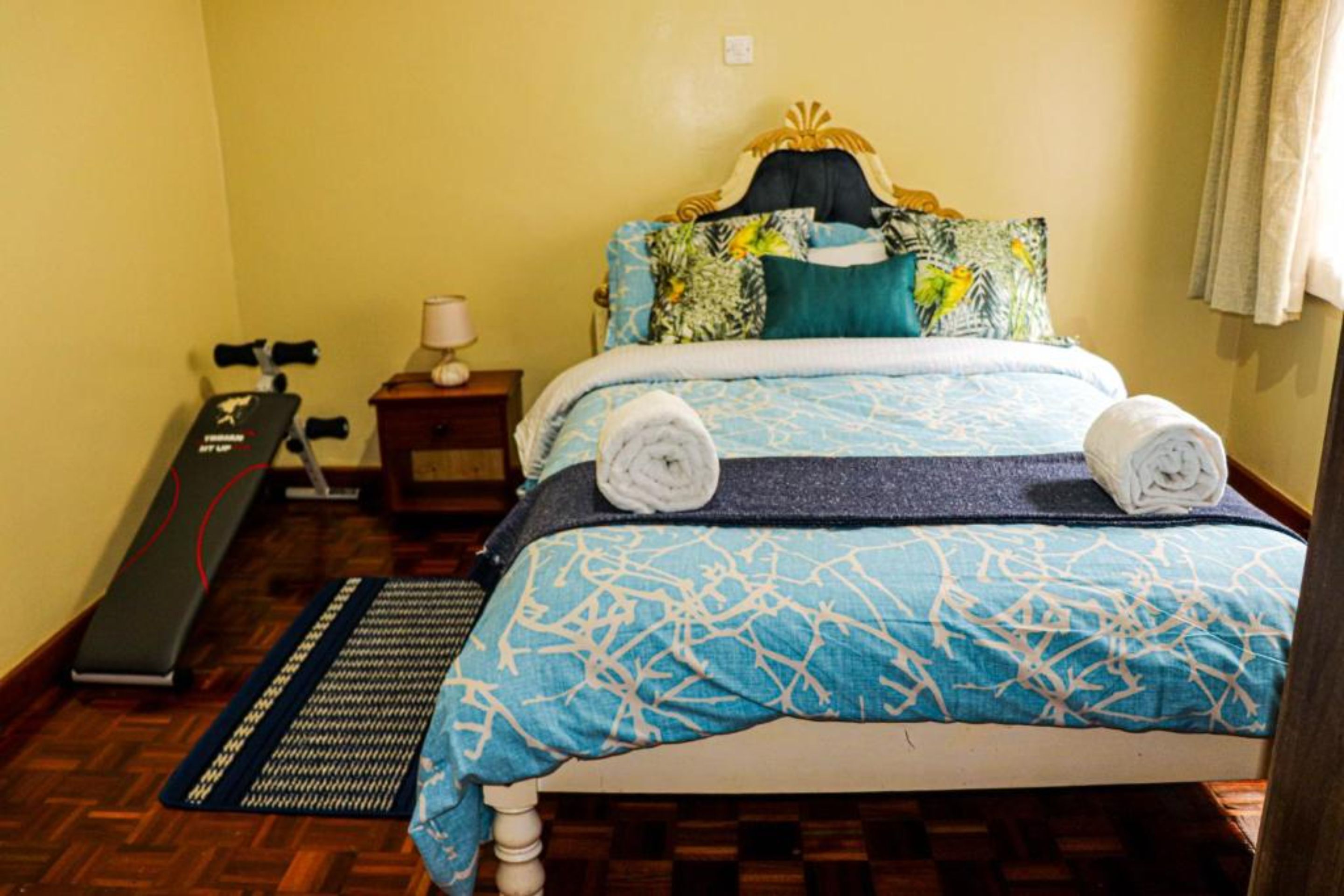 A bedroom with a bed, a treadmill, and a yoga mat.