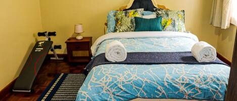 A bedroom with a bed, a treadmill, and a yoga mat.