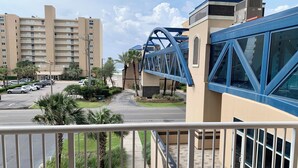 Een hotel met een modern design, met een opvallende blauwe brug, een parkeerplaats en uitzicht op een woongebied met hoogbouw.